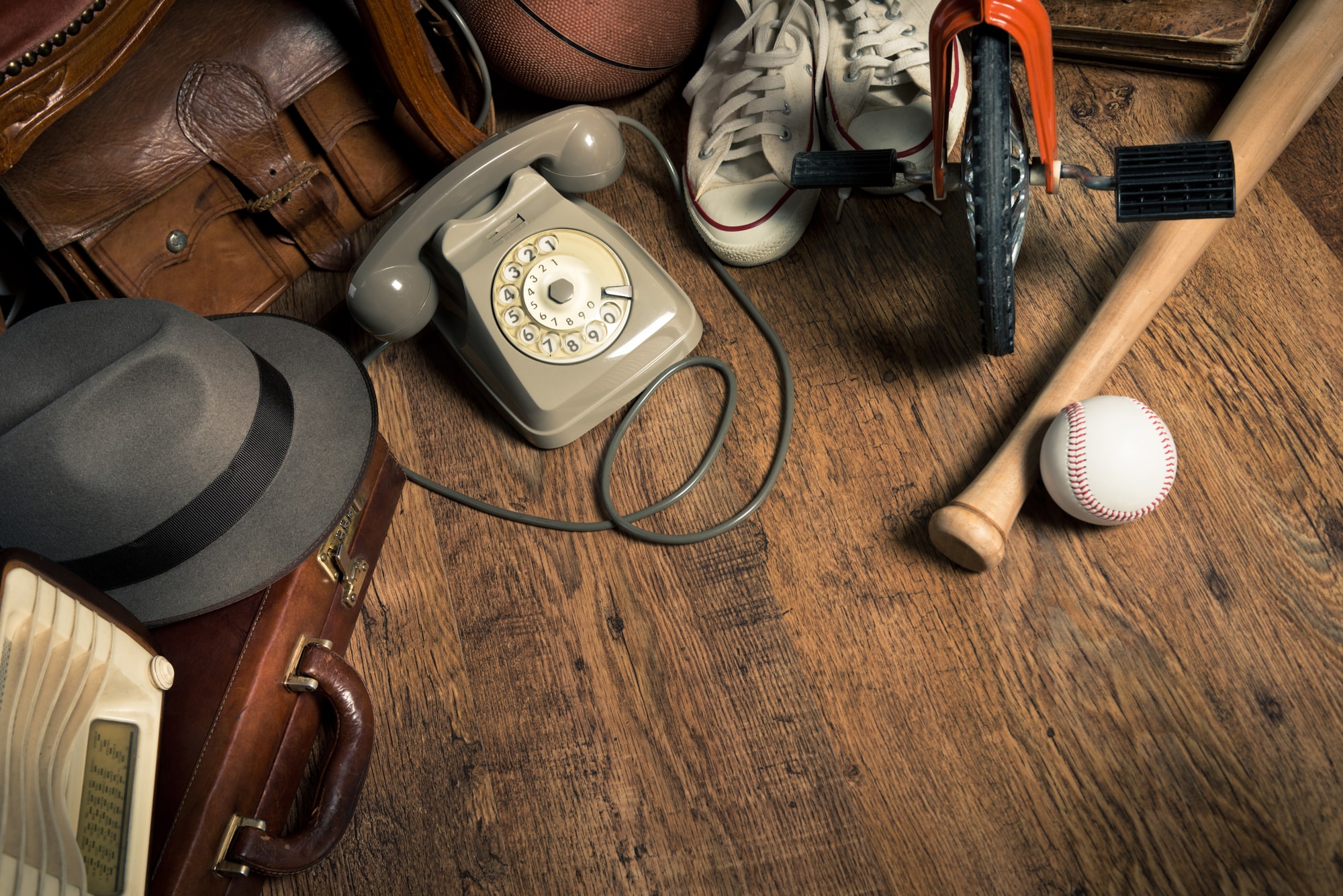  An old hat, telephone, suitcase, and bat and ball make up just some of the items cluttering an attic.